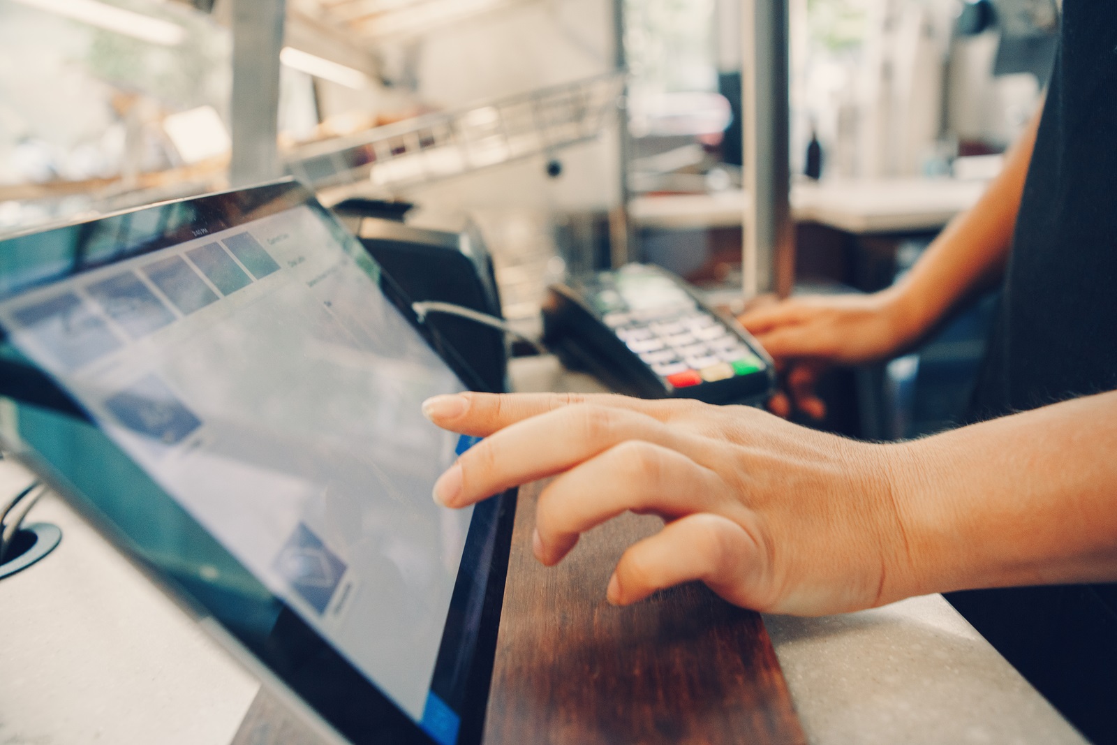 Closeup shot of caucasian cashier hands. Seller using touch pad for accepting client customer payment. Small business of coffee shop cafeteria.